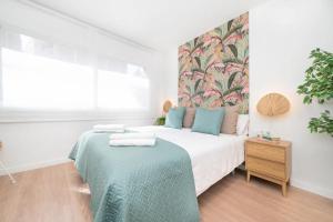 een witte slaapkamer met een bed met een blauwe deken bij Soler Apartments in Sant Adria de Besos