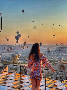 a woman standing on a balcony looking at hot air balloons at Takaev Cave House in Uçhisar