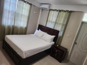 uma cama com lençóis brancos e almofadas num quarto em vacation home em Roseau