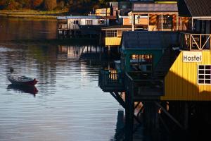 a small boat in the water next to a dock at Palafito Hostel Chiloé in Castro