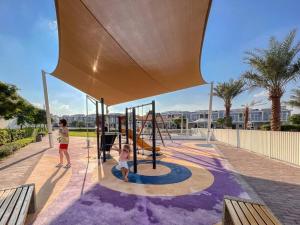 uma mulher e uma criança a brincar num parque infantil em Amal villa by escape time em Dubai