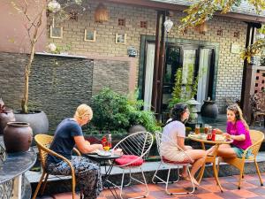 tres mujeres sentadas en una mesa en un patio en Nana Homestay & Villa en Hue