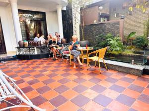 un grupo de personas sentadas en una mesa en un patio en Nana Homestay & Villa, en Hue