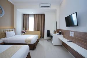 um quarto de hotel com duas camas e uma televisão de ecrã plano em Lorin Sentul Hotel em Bogor