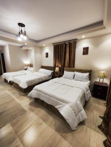 a bedroom with two beds and two lamps at Hur magic pyramids Hotel in Cairo