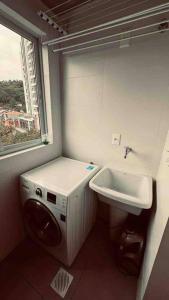 uma casa de banho com um lavatório e uma máquina de lavar roupa em Loft de Luxo na Vila Germânica em Blumenau