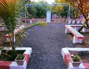 un parque con un banco y un columpio en Madhav Farmhouse en Sasan Gir