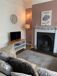 a living room with a fireplace and a television at Knutsford Cottage in Knutsford