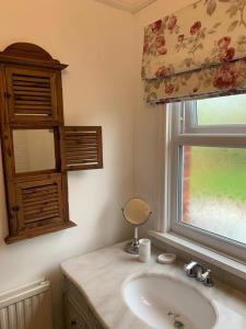 a bathroom with a sink and a window at Knutsford Cottage in Knutsford