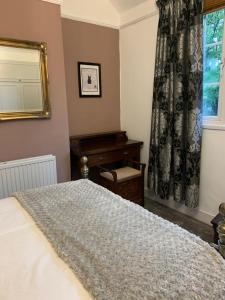 a bedroom with a bed and a desk and a window at Knutsford Cottage in Knutsford