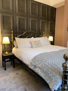 a bedroom with a bed with a large wooden headboard at Knutsford Cottage in Knutsford