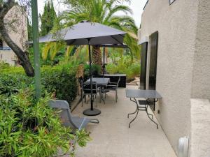 a patio with a table and chairs and an umbrella at St Raphaël 37m2, piscine, wifi, commerces mer 5mn à pieds in Saint-Raphaël