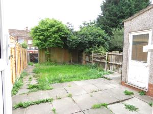einen Hinterhof mit einem Zaun und einem Garten mit Gras in der Unterkunft Tudors eSuites Four Bedroom House + Garden in Coventry