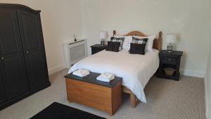 - une chambre avec un grand lit blanc et des oreillers noirs dans l'établissement Riverview Cottage, à Halkirk