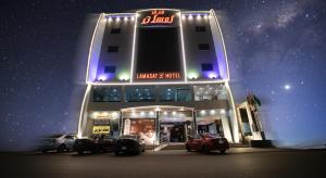 فندق لمسات نجران في نجران: مبنى فيه سيارات تقف امامه ليلا