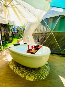 uma banheira debaixo de uma tenda com 2 copos de vinho em Aconchego no Domo com Ofurô 7,5km centro Águas de Lindoia com CORTESIA em Águas de Lindóia