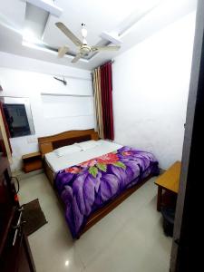 a bedroom with a bed with a purple comforter at HOTEL SHREE PRAYAG in Nāthdwāra