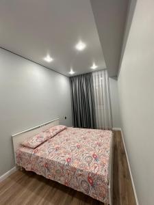 a bedroom with a bed with a colorful blanket at Aportament in Abyroy Residence in Atyrau
