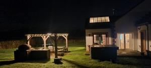 Auchendennan Farm Self Catering Cottages في بالوتش: حديقة خلفية في الليل مع شرفة ومنزل