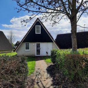 een huis met een zwart dak en een witte garage bij De Vecht, 124 - centraal gelegen aan vijver in Gramsbergen