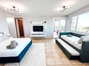 a living room with two beds and a tv at Oasis Village Spacious Apt W/ Ocean View For 9 in Rio Grande