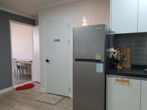 a kitchen with a refrigerator next to a door at Rest place with beautiful flowers in Daegu