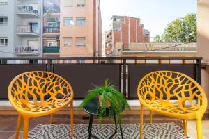 twee gele stoelen en een plant op een balkon bij Soler Apartments in Sant Adria de Besos