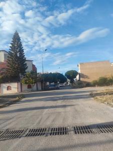 una calle vacía con un árbol y un edificio en Tiba soliman plage, en Nabeul