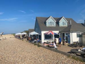 a group of people sitting outside a building on the beach at Ocean Cottage, Ferring - seaside cottage moments from the beach and Bluebird cafe in Ferring