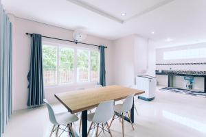 una sala da pranzo con tavolo in legno e sedie bianche di AABAN House 03 a Hat Yai