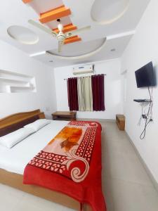 a bedroom with a bed with a red blanket at HOTEL SHREE PRAYAG in Nāthdwāra