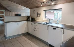 a kitchen with white cabinets and a sink and a window at Nice Home In Kpingsvik With Sauna in Grönskog