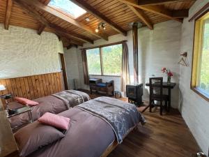 a bedroom with two beds and a desk and windows at Hostería Hotel Cuello de Luna - Cotopaxi - Country Inn in Lasso