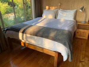 a bed in a room with a large window at Forestiva Farm - River Cottage in Centurion