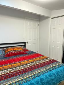 a bed with a colorful blanket on it in a room at Schunemunk Mnt hse 15 mins to Legoland &woodbury in Monroe