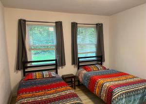 two beds in a room with two windows at Schunemunk Mnt hse 15 mins to Legoland &woodbury in Monroe