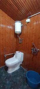 a bathroom with a toilet in a wooden wall at TREE HOUSE BY THE CITY ESCAPE in Shimla