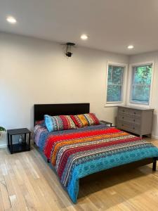 Schunemunk Mnt hse 15 mins to Legoland &woodbury في مونروه: غرفة نوم مع سرير وبطانية ملونة ونوافذ