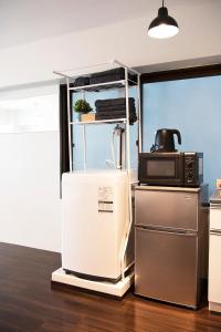 a kitchen with a microwave on top of a refrigerator at #2 3stops to Shinjuku station stylish spacious studio apartment in Tokyo