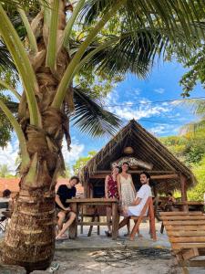 a group of people sitting on a picnic table under a palm tree at Pousada Moreré in Ilha de Boipeba