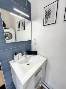 La salle de bains est pourvue d'un lavabo blanc et d'un miroir. dans l'établissement PLACE - Appartement lumineux au coeur de la Joliette, à Marseille