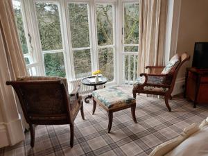een kamer met 2 stoelen, een tafel en ramen bij Ambleside Manor - Vegetarian B&B in Ambleside