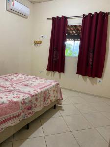 Habitación con 1 cama y 2 cortinas rojas en Casa paraíso Paraty, en Paraty