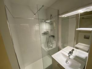 La salle de bains blanche est pourvue d'un lavabo et d'une douche. dans l'établissement Sol-y-Days Cigales de Mer 1 nuit tout inclus, au Grau-du-Roi