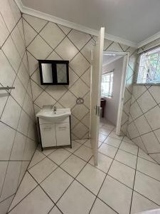 a bathroom with a sink and a tiled wall at 9 wena Ave Guesthouse in Klerksdorp +75 photos