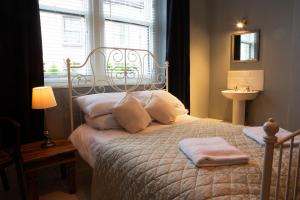 1 dormitorio con 1 cama con ventana y lavamanos en Kings Arms Hotel en Ulverston