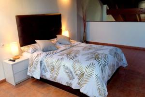 1 cama con edredón blanco y mesita de noche en Dúplex rodeado de naturaleza, bodegas e historia, en Sojuela