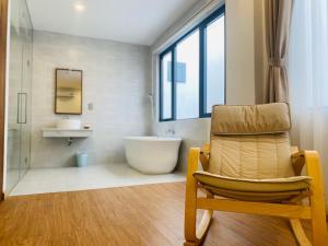 a bathroom with a tub and a chair and a sink at Hill Star Hotel Phu Quoc in Phu Quoc +100 photos