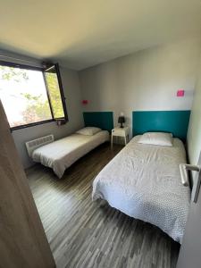 a bedroom with two beds and a window at Gîte La Cerise Qui Rit in La Cresse
