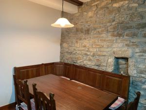 a dining room with a wooden table and a stone wall at Casa Altemir in Campo